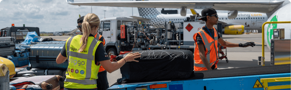 Ramp employees loading luggage off plane